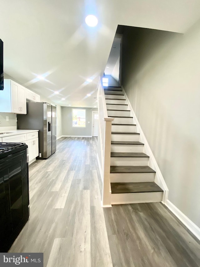 staircase featuring wood-type flooring and sink