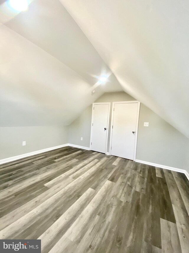 additional living space with vaulted ceiling and dark hardwood / wood-style flooring