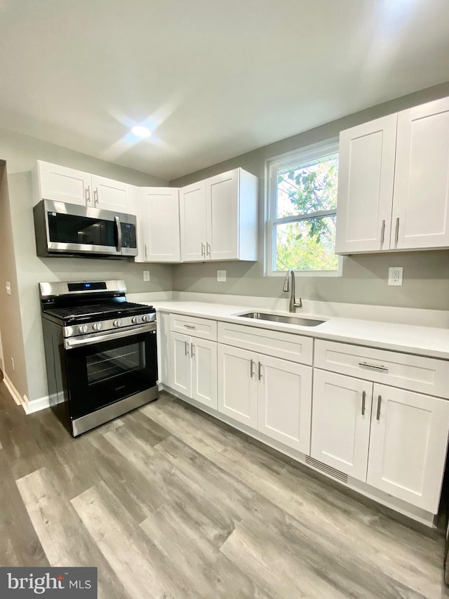 kitchen featuring light hardwood / wood-style floors, stainless steel appliances, sink, and white cabinets