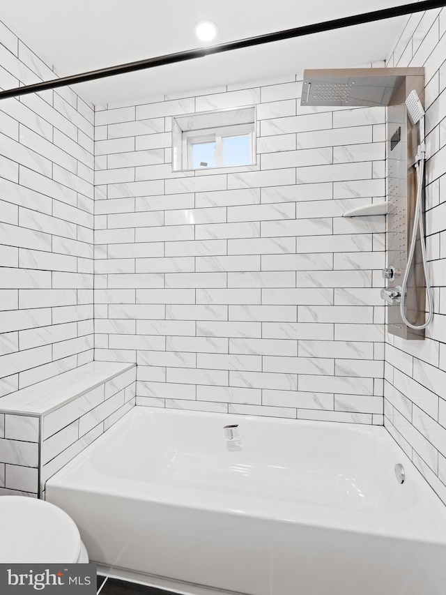 bathroom featuring tiled shower / bath combo and toilet