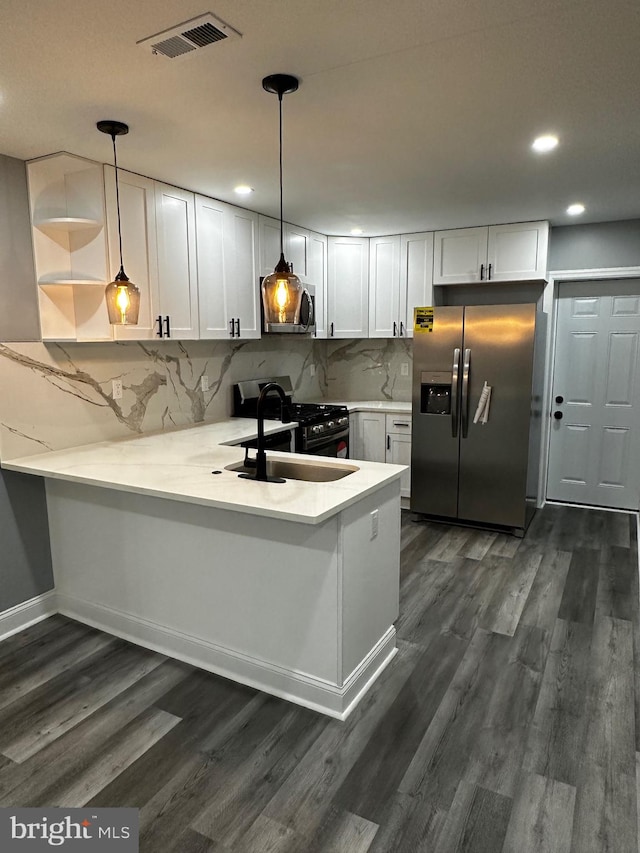 kitchen with stainless steel appliances, sink, kitchen peninsula, hanging light fixtures, and white cabinets