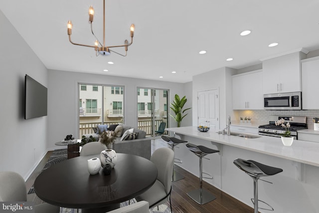 dining area featuring dark wood-type flooring, sink, and a chandelier