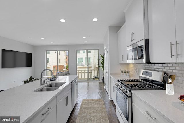 kitchen featuring white cabinets, light stone countertops, dark wood-type flooring, sink, and stainless steel appliances