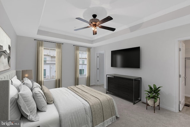 bedroom with ornamental molding, light carpet, ceiling fan, and a raised ceiling