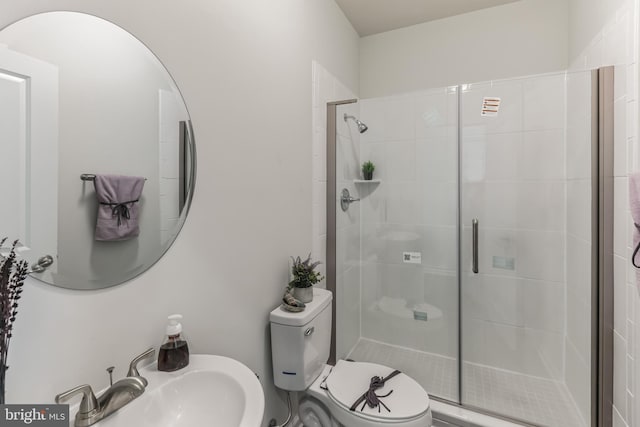 bathroom with toilet, a shower with shower door, and sink