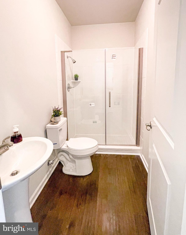 bathroom with a shower with door, hardwood / wood-style floors, and toilet