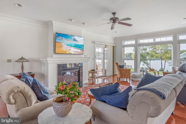 living room with a high end fireplace, hardwood / wood-style floors, crown molding, and ceiling fan