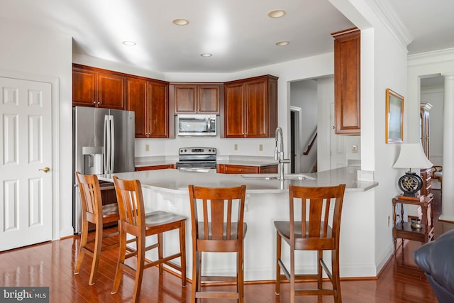 kitchen featuring sink, kitchen peninsula, a kitchen breakfast bar, hardwood / wood-style floors, and stainless steel appliances