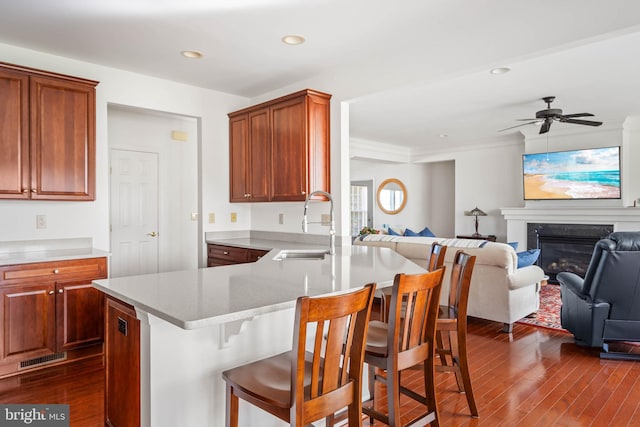 kitchen with dark hardwood / wood-style floors, a kitchen breakfast bar, kitchen peninsula, sink, and ceiling fan