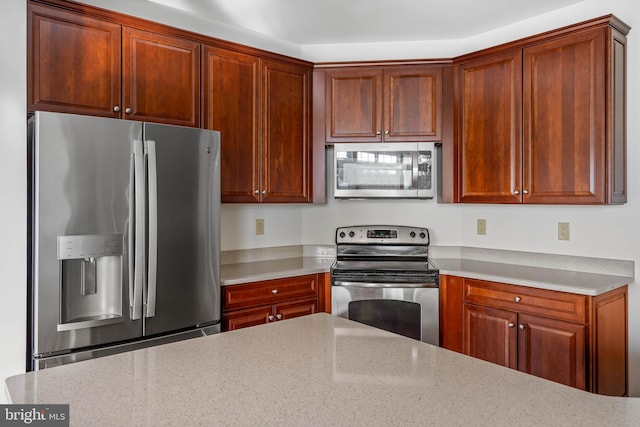 kitchen with light stone counters and appliances with stainless steel finishes