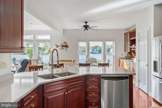 kitchen with light hardwood / wood-style flooring, sink, appliances with stainless steel finishes, a water view, and ceiling fan