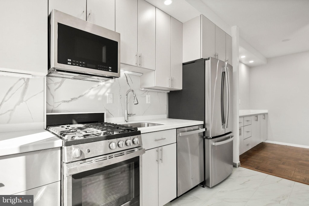 kitchen with white cabinetry, appliances with stainless steel finishes, sink, and decorative backsplash