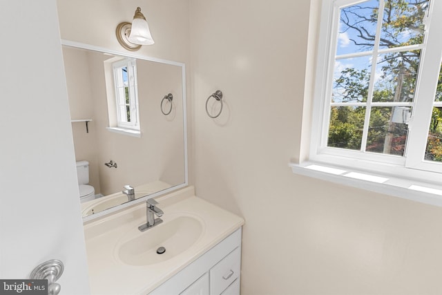 bathroom with vanity, toilet, and a healthy amount of sunlight