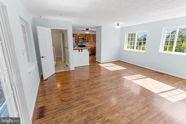 unfurnished living room featuring ceiling fan, dark hardwood / wood-style floors, and a textured ceiling