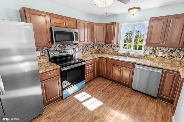 kitchen with hardwood / wood-style flooring, appliances with stainless steel finishes, sink, and decorative backsplash