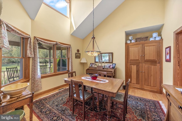 dining room with wood-type flooring and high vaulted ceiling