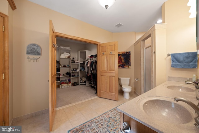 bathroom with toilet, a shower with shower door, vanity, and tile patterned flooring