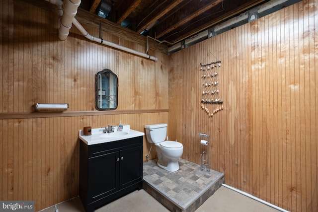 bathroom with toilet, wood walls, and vanity