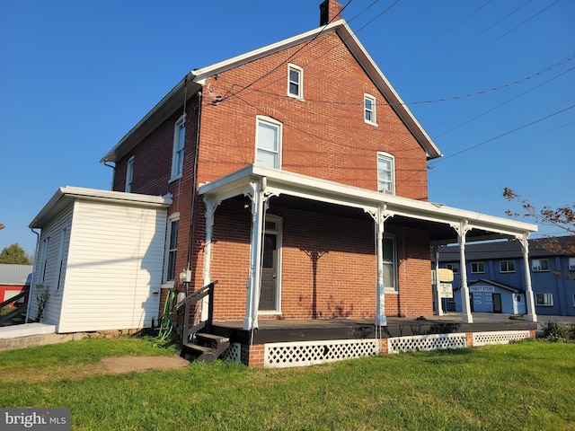 rear view of property with covered porch and a lawn