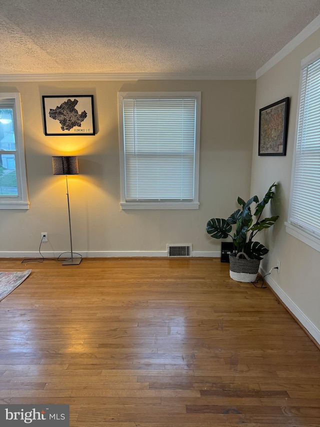 spare room with ornamental molding, a textured ceiling, and hardwood / wood-style flooring