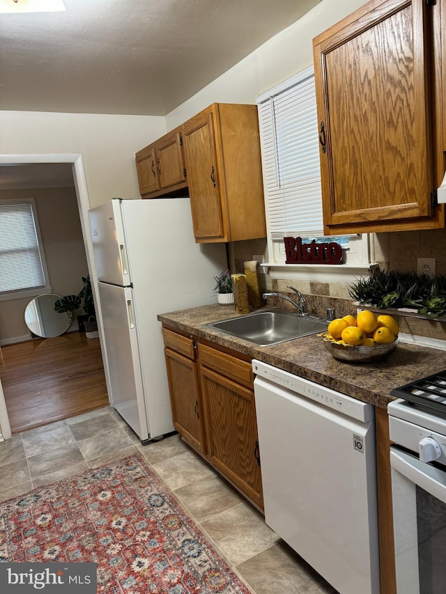 kitchen featuring tasteful backsplash, exhaust hood, light wood-type flooring, sink, and white appliances