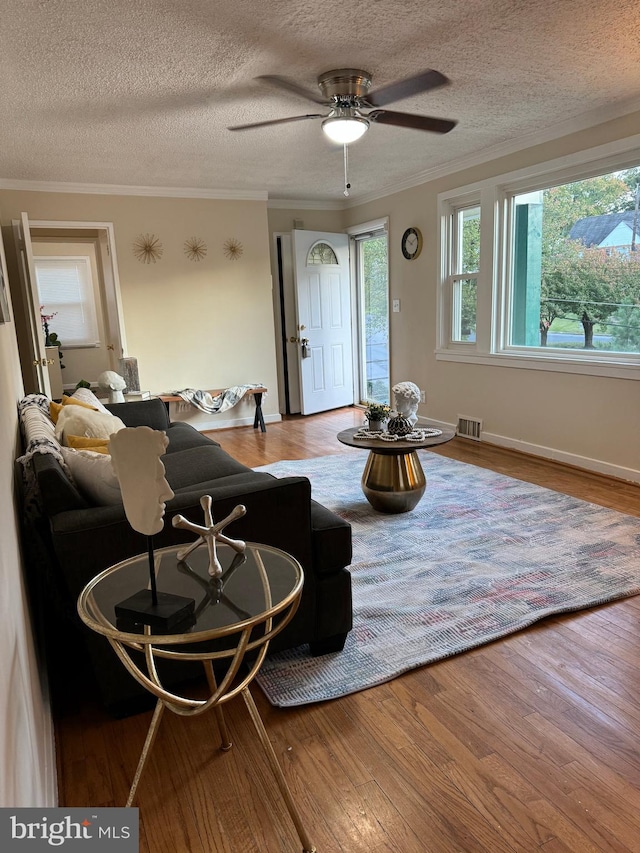 living room with a textured ceiling, crown molding, hardwood / wood-style flooring, and ceiling fan