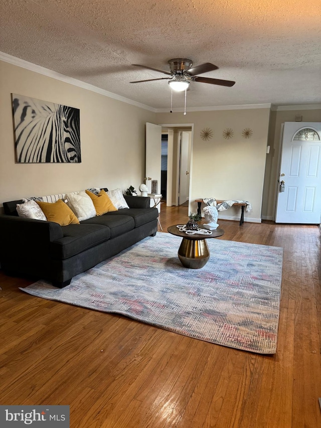 living room featuring hardwood / wood-style floors, crown molding, a textured ceiling, and ceiling fan