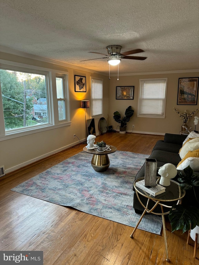 living room featuring crown molding, a textured ceiling, wood-type flooring, and ceiling fan