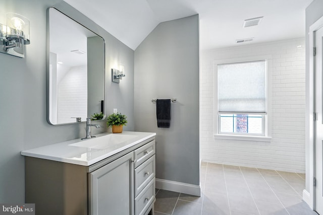 bathroom with tile patterned floors, vanity, and vaulted ceiling