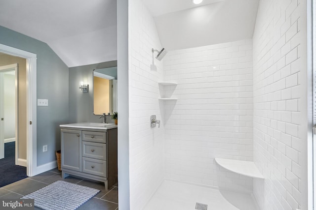 bathroom featuring tile patterned flooring, vaulted ceiling, vanity, and tiled shower