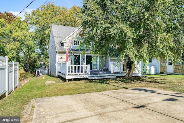 obstructed view of property with a front yard, a wooden deck, and a patio