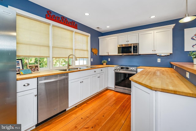 kitchen featuring pendant lighting, butcher block countertops, and appliances with stainless steel finishes