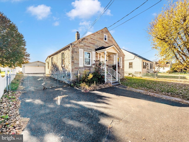 bungalow-style house featuring covered porch, an outbuilding, and a garage