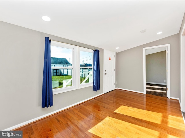 empty room with hardwood / wood-style floors and lofted ceiling