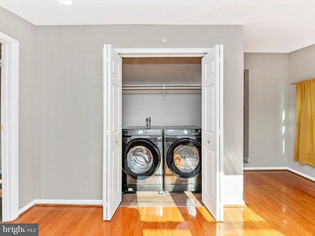 clothes washing area with washer and dryer and hardwood / wood-style flooring