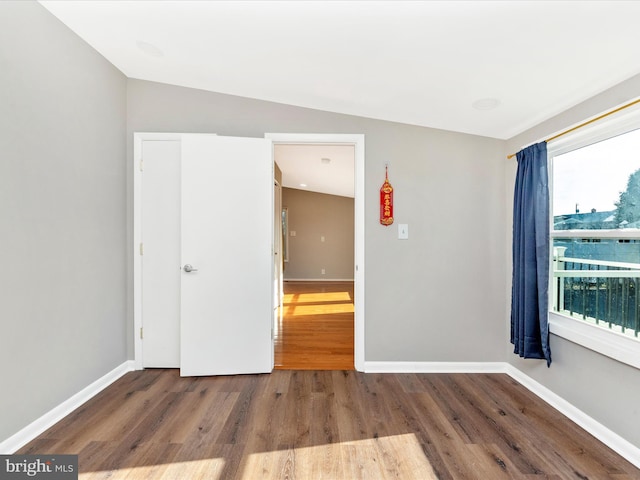 unfurnished room with hardwood / wood-style floors, a healthy amount of sunlight, and vaulted ceiling