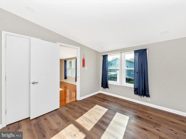 unfurnished room featuring dark hardwood / wood-style floors and vaulted ceiling