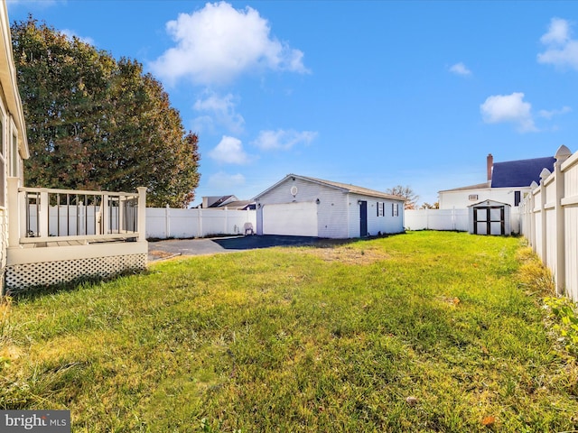 view of yard featuring a shed, a garage, and a wooden deck