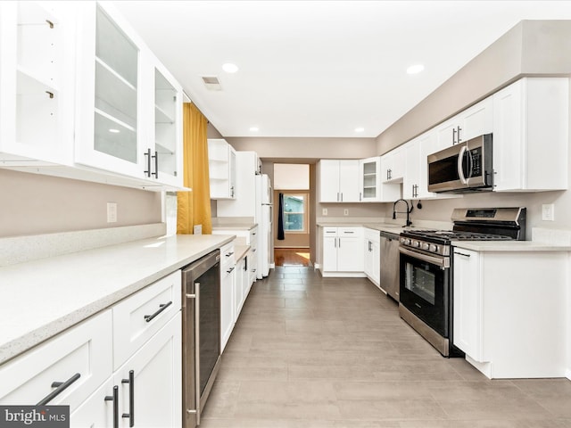 kitchen featuring wine cooler, white cabinetry, sink, and stainless steel appliances