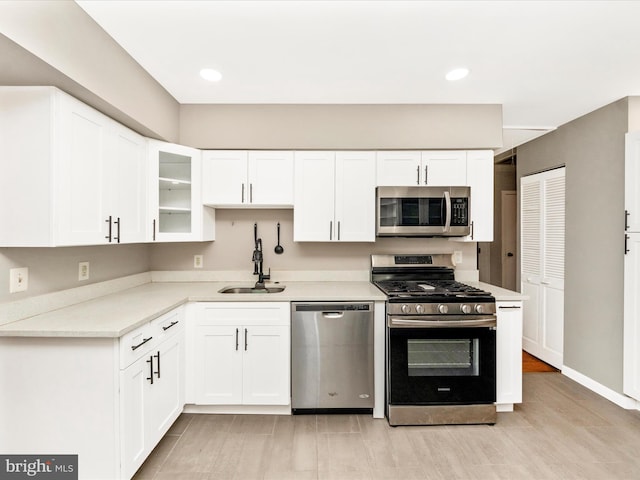 kitchen with white cabinets, sink, light wood-type flooring, and stainless steel appliances