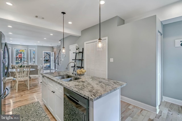 kitchen featuring sink, hanging light fixtures, black dishwasher, an island with sink, and white cabinets