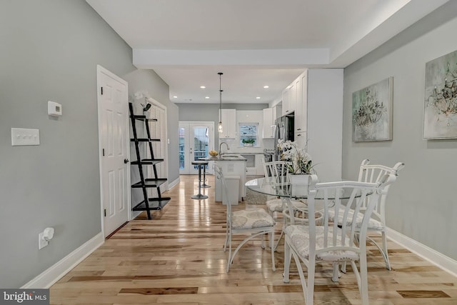 dining space with french doors, light hardwood / wood-style floors, and sink