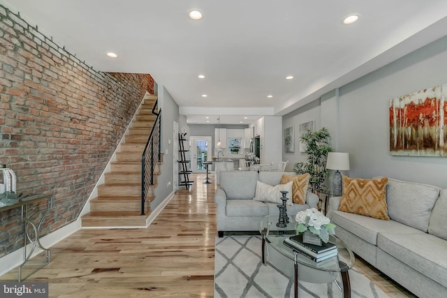 living room featuring brick wall and light wood-type flooring