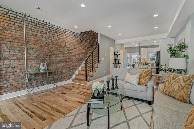 unfurnished living room featuring light wood-type flooring and brick wall