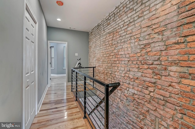 hallway featuring brick wall and light wood-type flooring