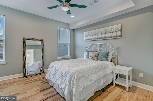 bedroom with multiple windows, ceiling fan, and hardwood / wood-style floors