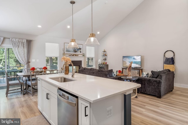 kitchen featuring white cabinetry, stainless steel dishwasher, sink, pendant lighting, and a center island with sink