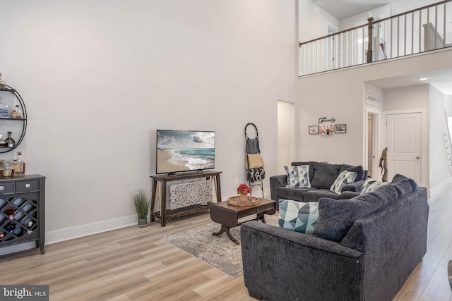 living room with light hardwood / wood-style floors and a high ceiling