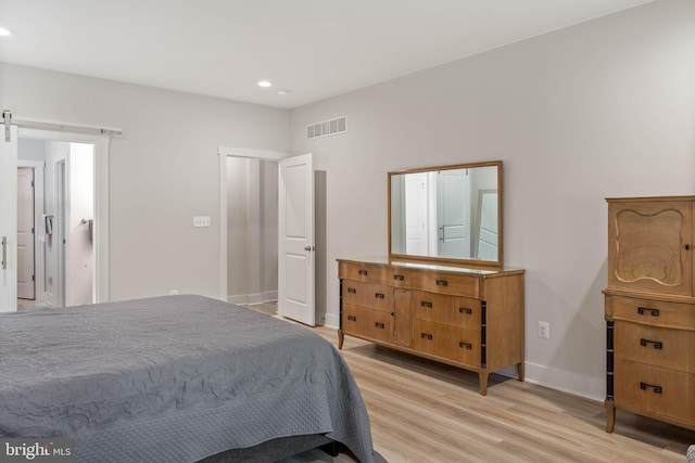 bedroom with light hardwood / wood-style floors and a barn door