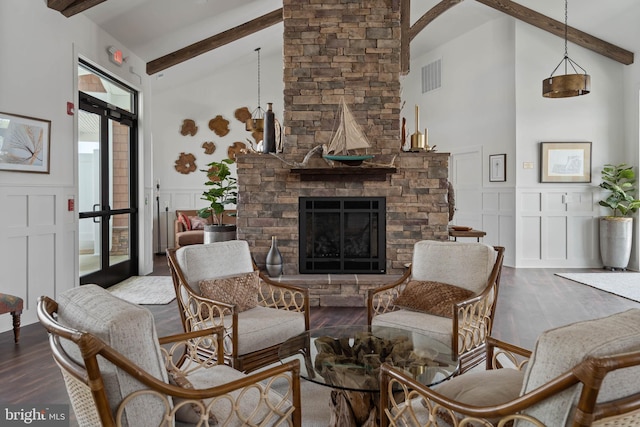 living room featuring hardwood / wood-style flooring, a stone fireplace, beam ceiling, and high vaulted ceiling